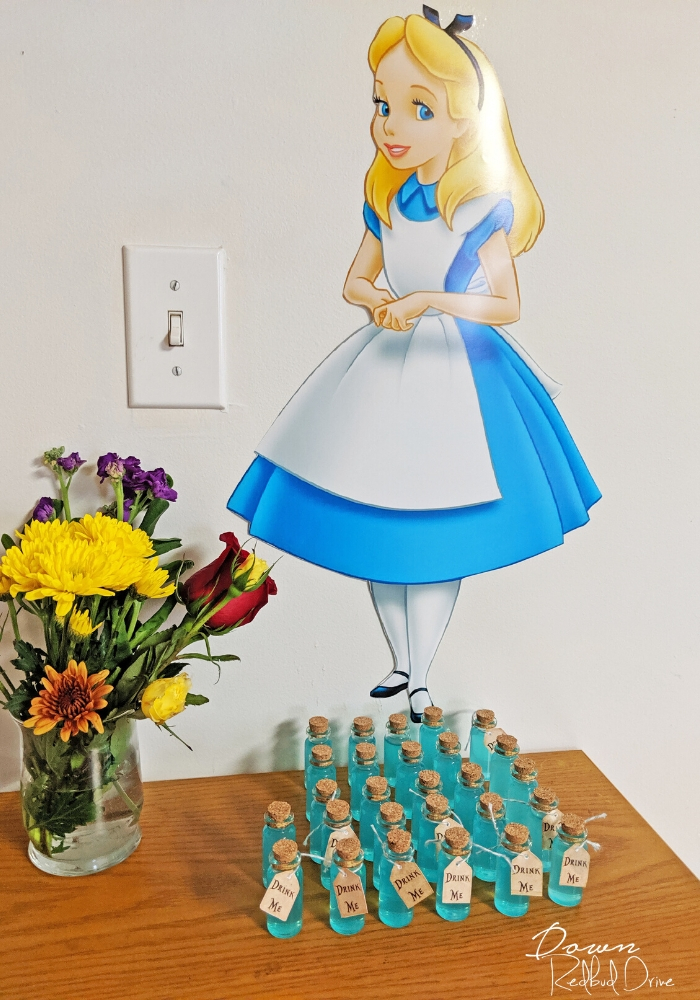 alice in wonderland wall cutout with drink me bottles on a wooden table