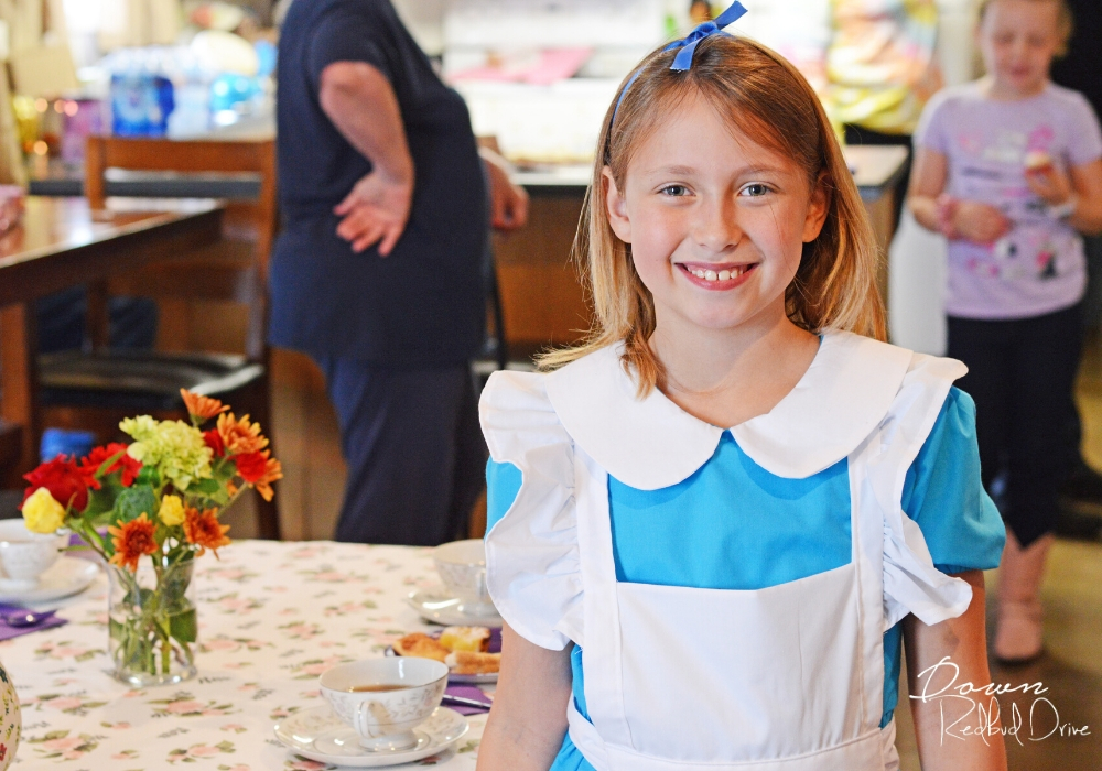 little girl dressed in alice in wonderland costume at an alice in wonderland birthday party