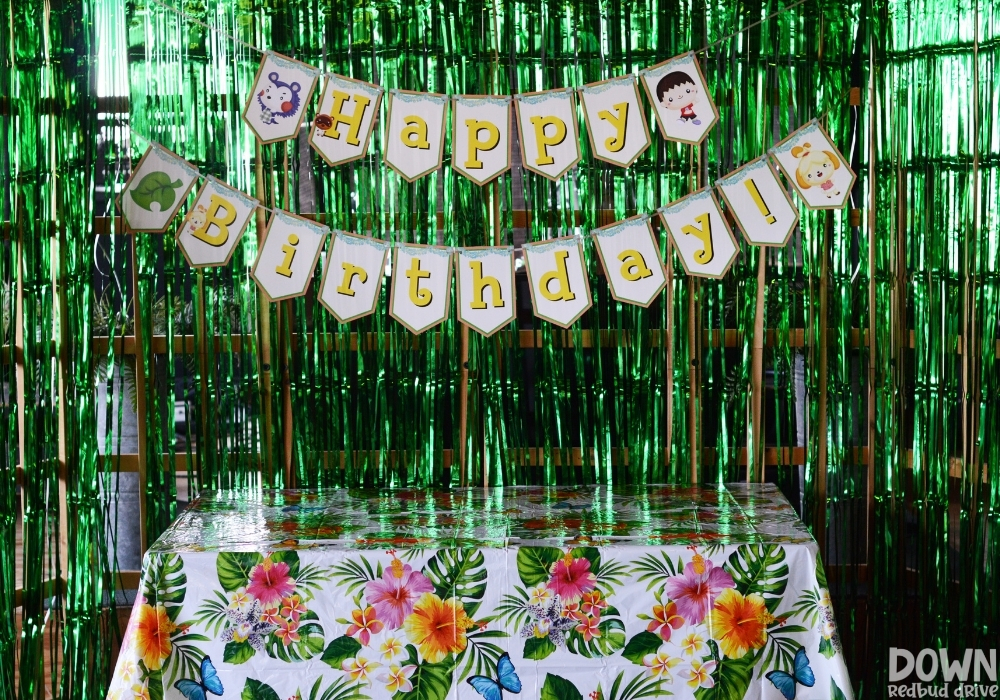 A printable Animal Crossing "Happy Birthday" banner over a tropical themed gift table.