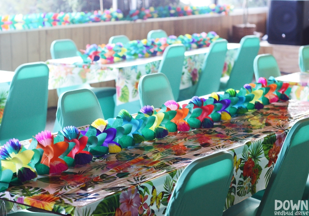 A flower centerpiece laying on a tropical themed table cloth.