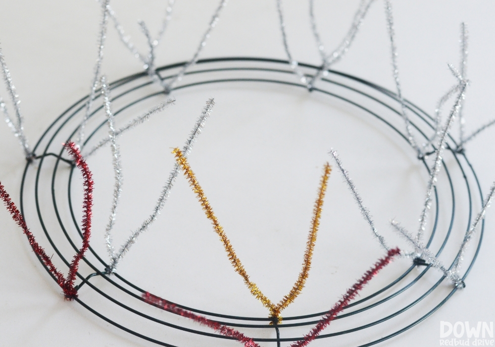 Red, gold and silver pipe cleaners attached to a wreath form to make a mesh wreath.