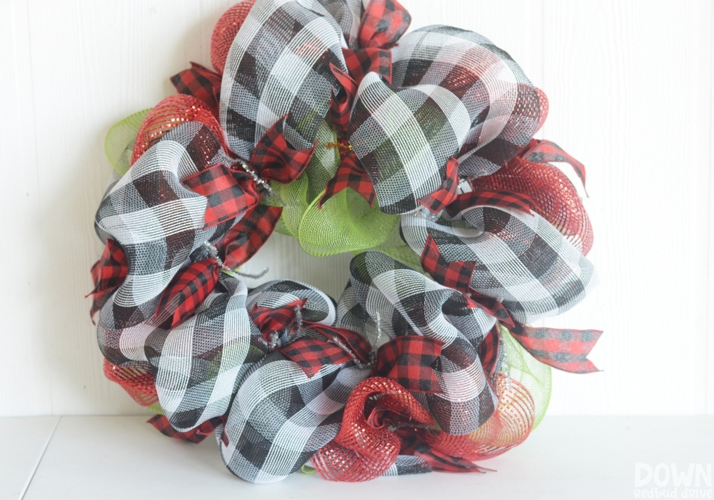 The wreath form with red and white buffalo check ribbon attached to it.