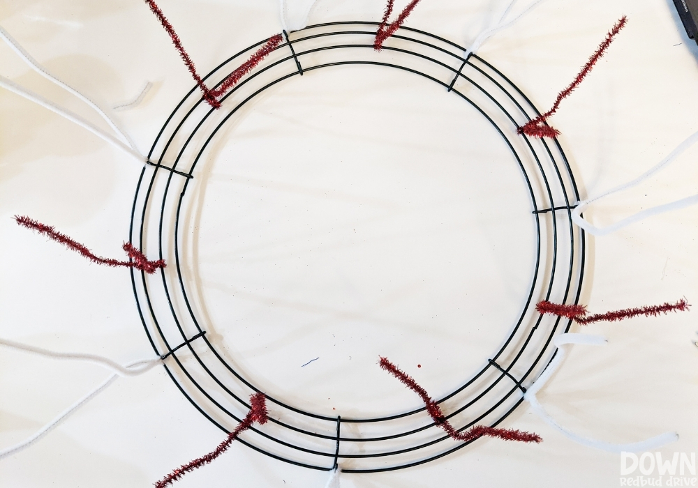 Overhead view of red and white chenille stem pipe cleaners attached to a wreath form.