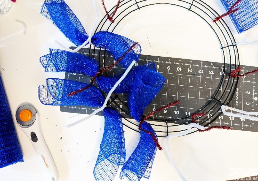 Overhead view of blue deco mesh being attached to a wreath form.