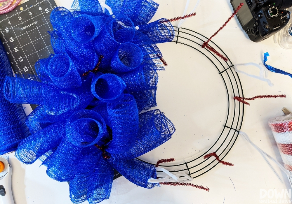 Overhead view of half of a wreath form covered in blue deco mesh.