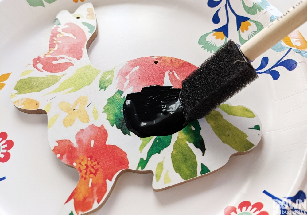 Close up of a wooden bunny decoration being painted black.