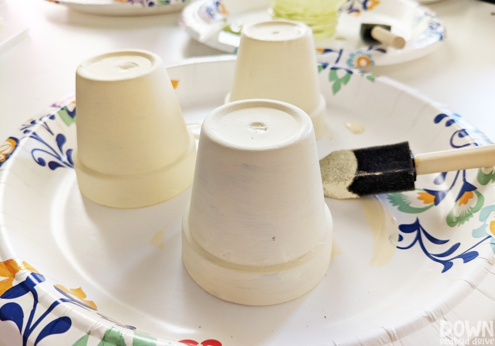 Clay pots painted white on a paper plate.