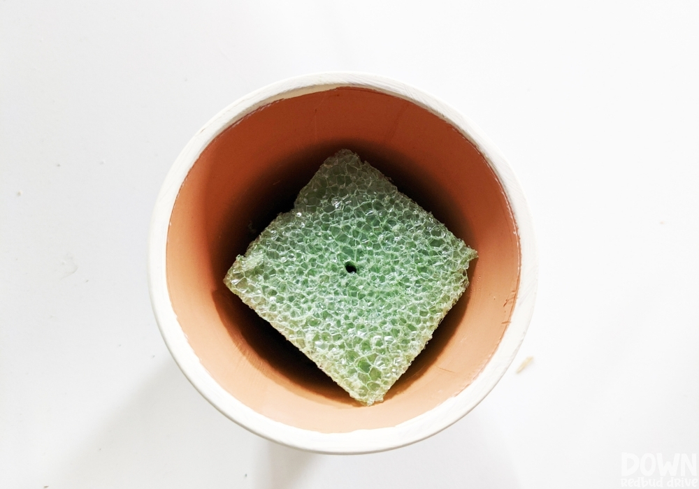 A piece of floral foam in a clay pot.