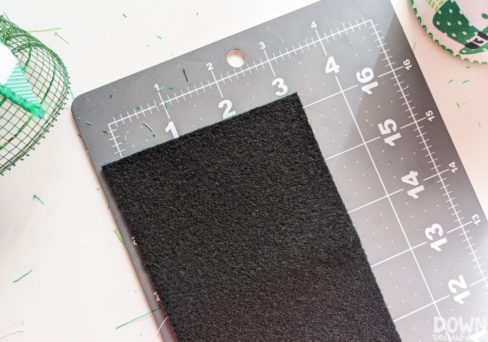 Using a cutting mat to measure and cut black felt.