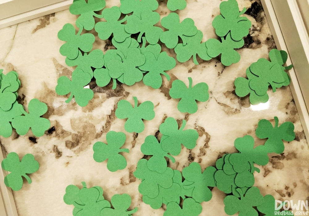 Overhead view of filling the art frame with shamrock part cut outs.