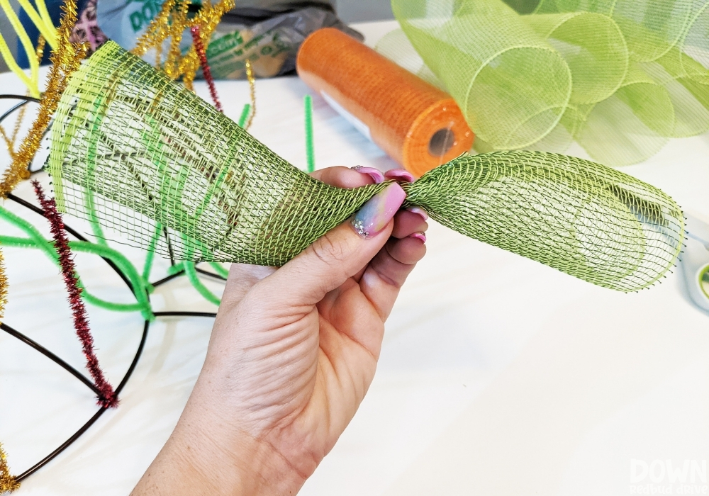 Green deco mesh bunched up to be attached to a wreath form for the deco mesh pumpkin wreath.