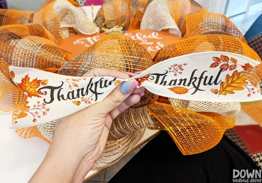 The "Thankful" ribbon pinched together to be attached to the DIY Thanksgiving Mesh Wreath.