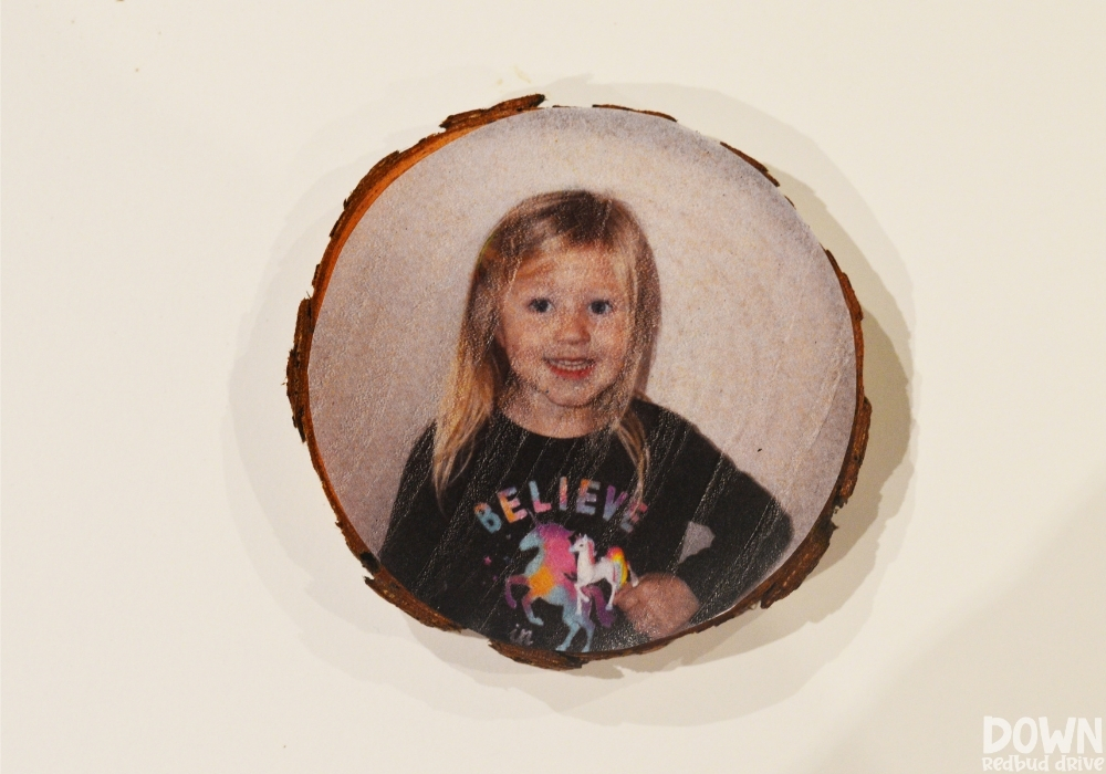 A tissue paper picture applied to a wood slice ornament using Modge Podge.