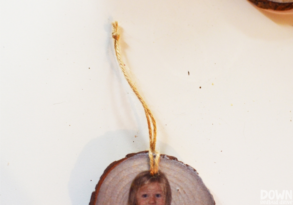 A piece of twine tied through the hole of the DIY Wood Photo Ornament in order to hang it.