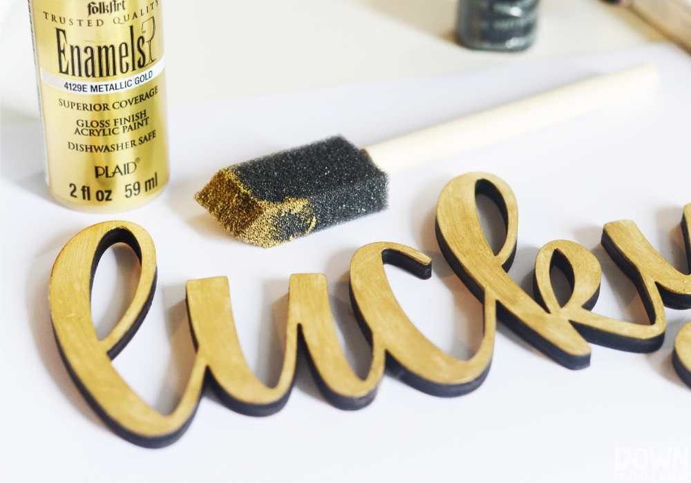 A wooden cut out of the word "lucky" painted gold.