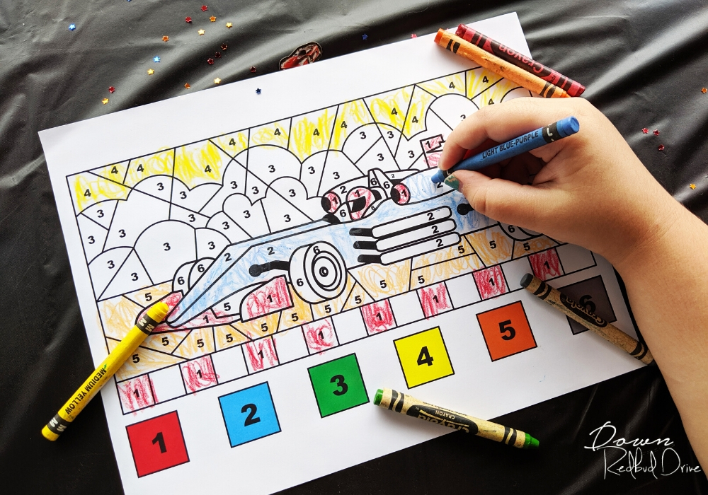 child's hand coloring a color-by-number racecar coloring sheet