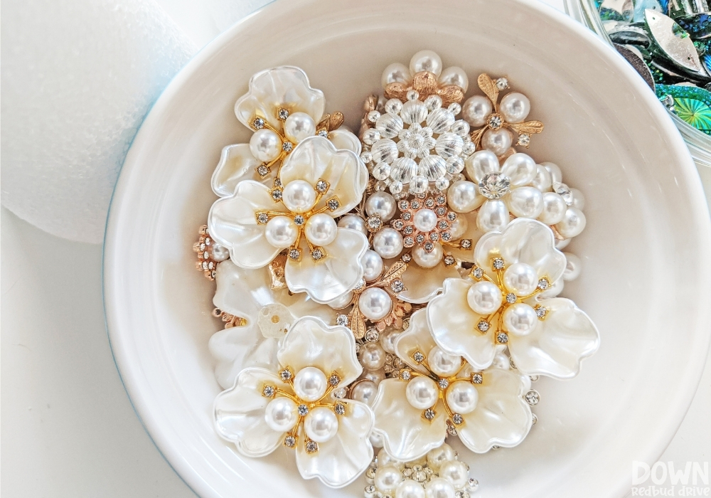 A white bowl of jewels and rhinestones.