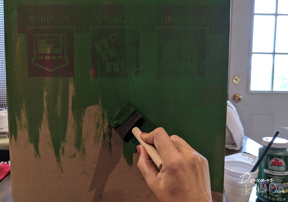 hand using a foam paint brush painting a box green