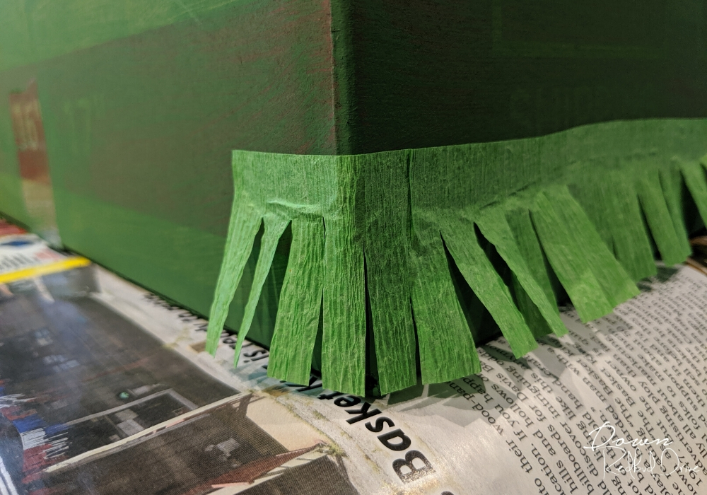 corner of a green painted box with fringer paper glued to the corner