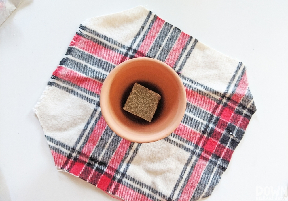 Overhead shot of the pot for the money Christmas tree gift DIY about to be wrapped in plaid fabric.