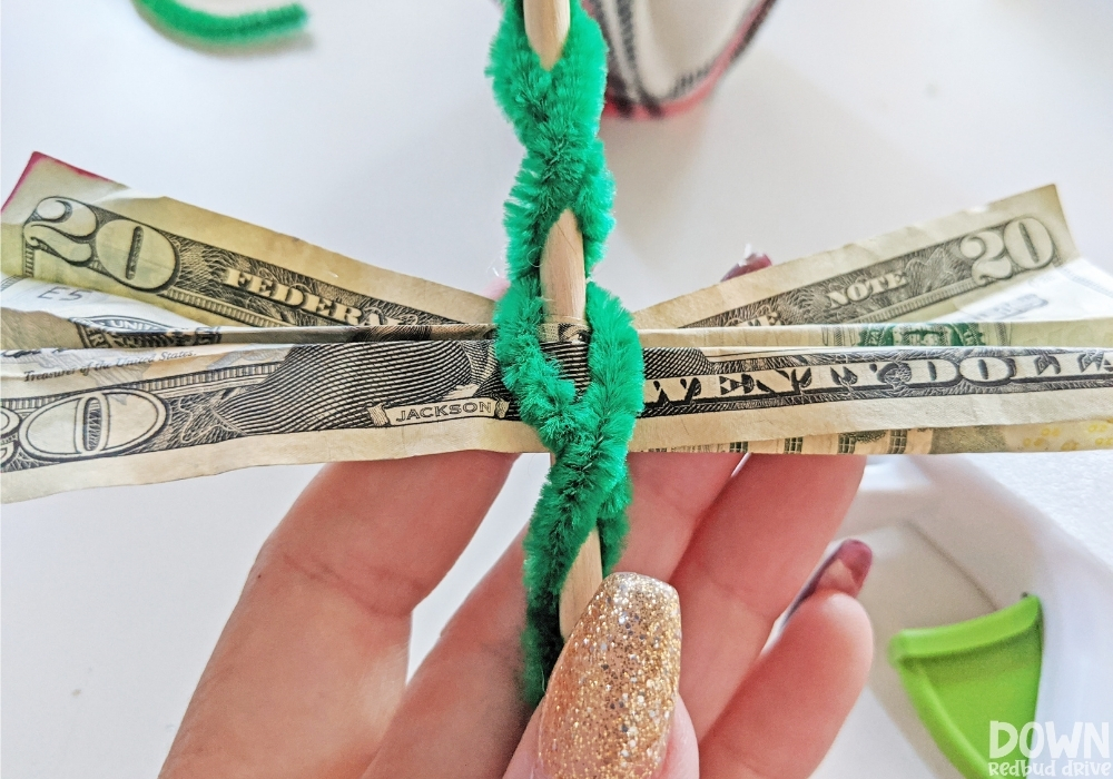 Closeup of the money inserted into the pipe cleaners of the money Christmas tree gift.