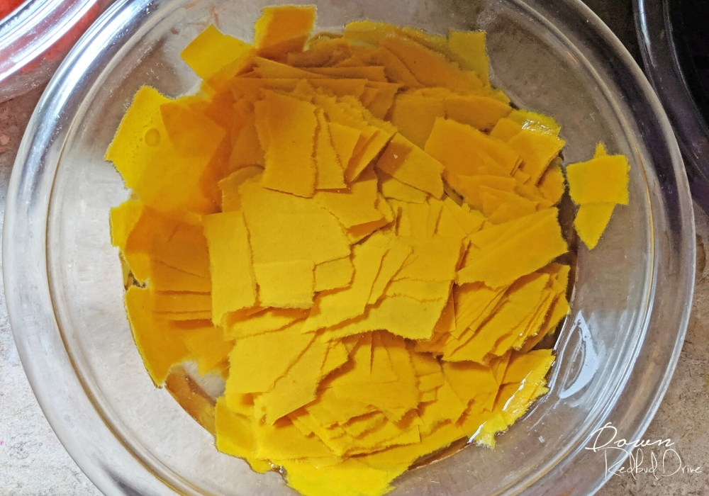 pieces of yellow construction paper soaking in a blow of water