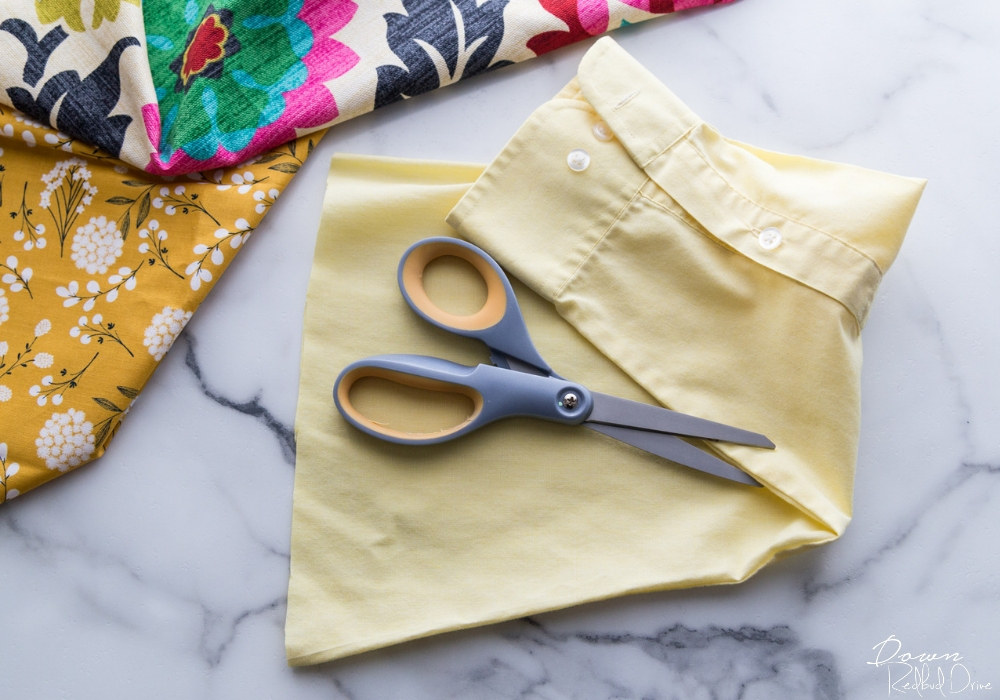 scissors sitting on top of a cut off shirt sleeve