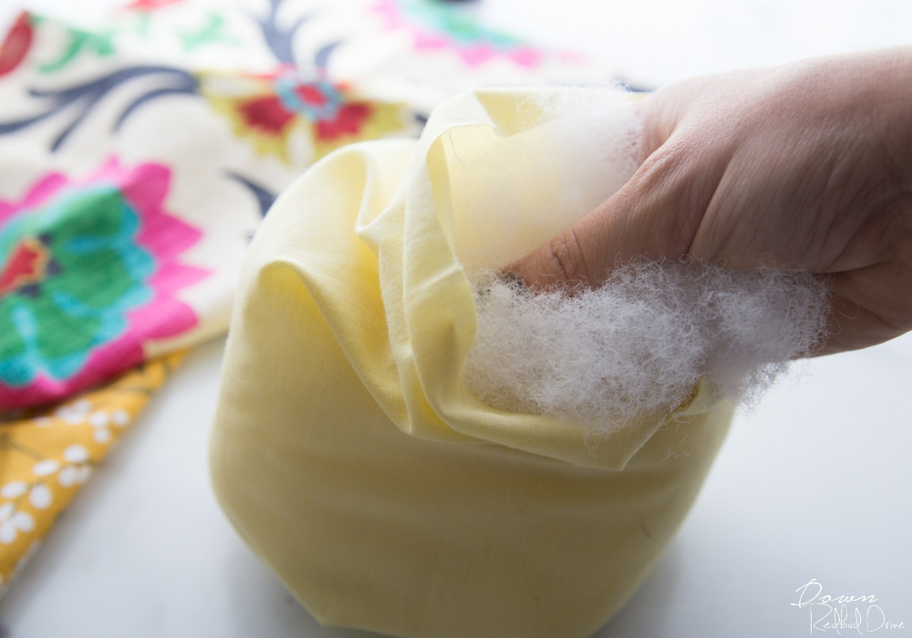 putting poly-fill into a yellow fabric pumpkin