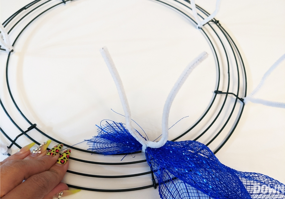 A piece of deco mesh attached to a wreath form with a chenille stem pipe cleaner.