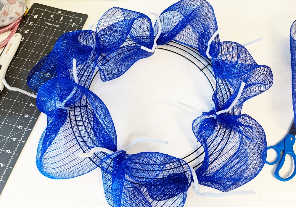 Blue deco mesh attached to a wreath form with white chenille stem pipe cleaners.