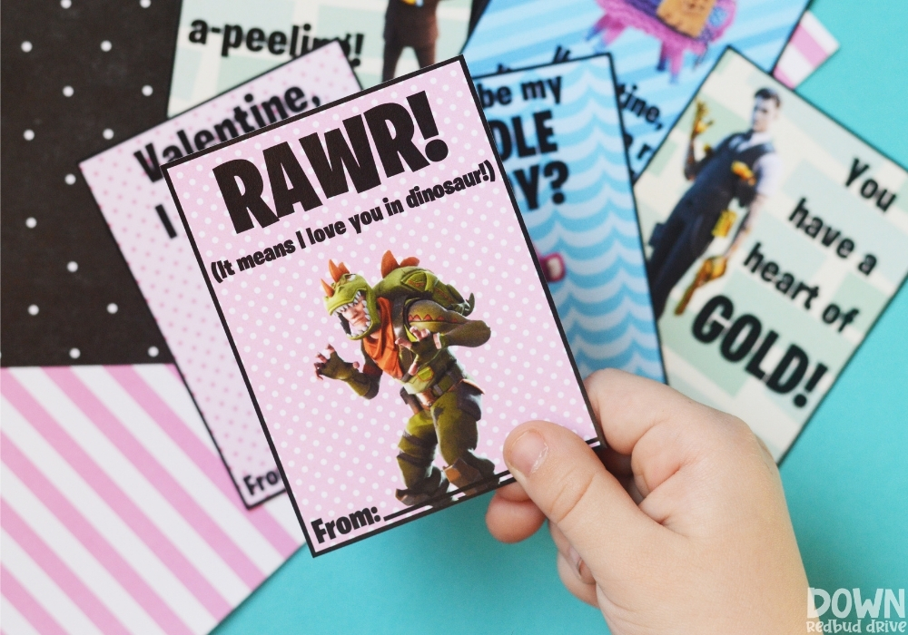 A close up of a child holding a valentine that says "Rawr! (It means I love you in dinosaur)" on it.