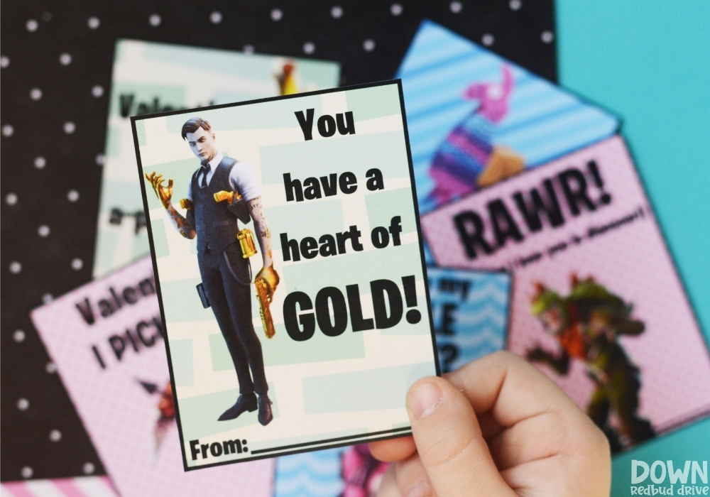 A close up of a child holding a valentine that says "You have a heart of GOLD!" on it.