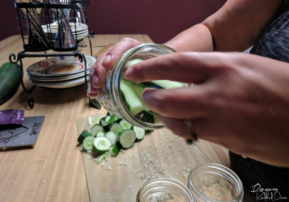 stuffing mason jars full of cucumber slices for making pickles