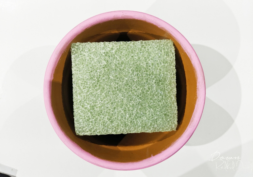 square piece of floral foam in a small pink flower pot from overhead