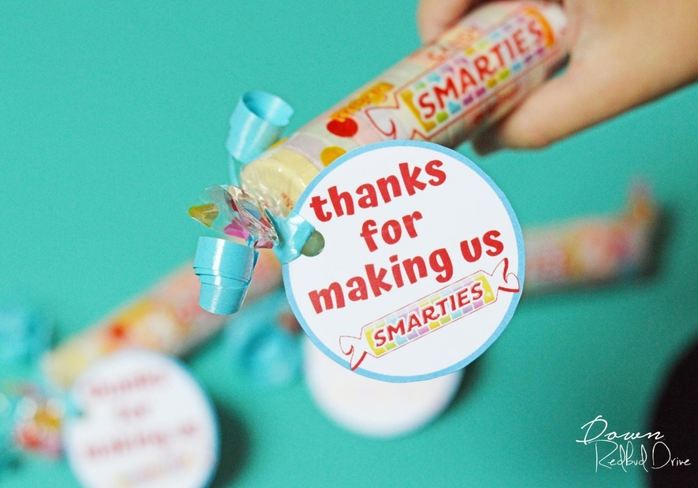 Overhead shot of child's hand holding the Smarties candy teacher's gift.