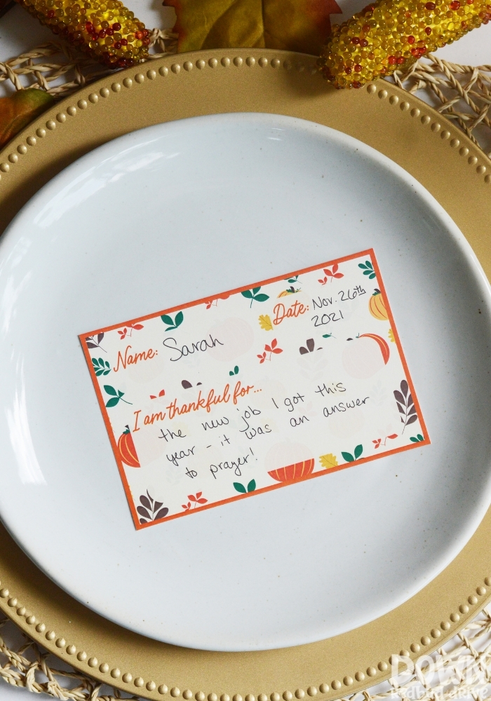 A tall closeup of a filled out Thanksgiving thankful place card.