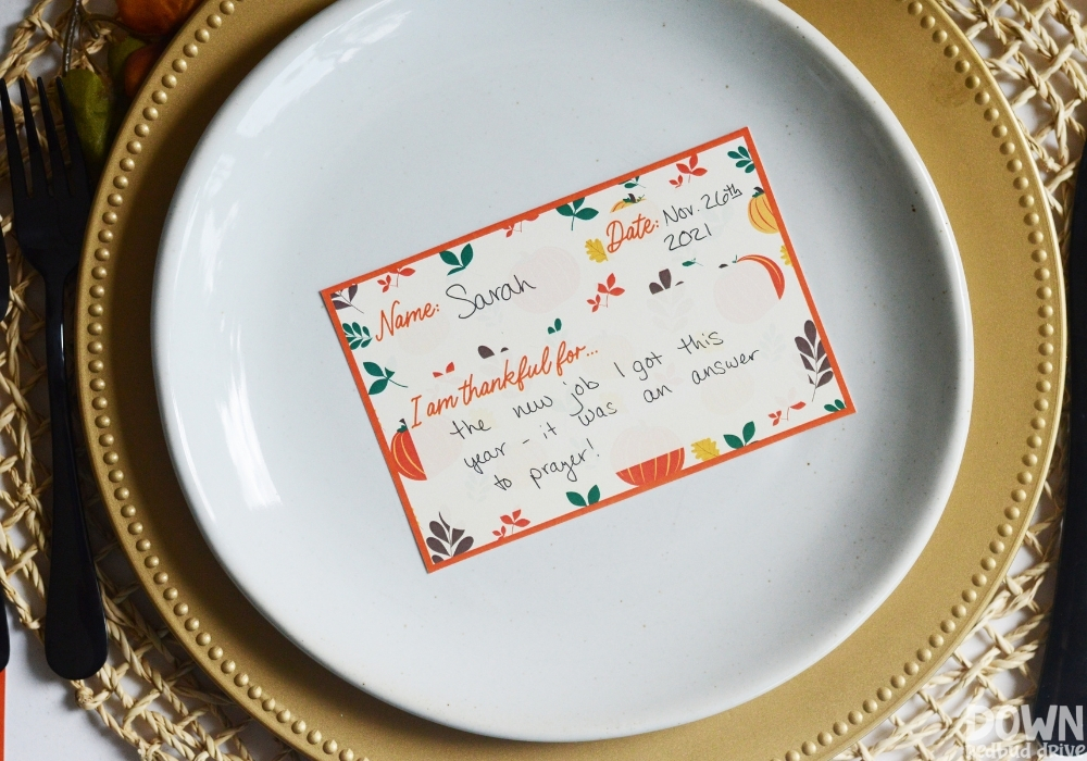 A thankful place card filled out on a thanksgiving table.