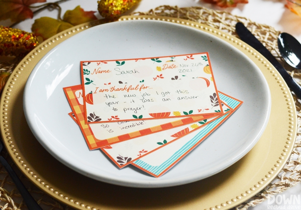 The filled out Thanksgiving thankful place cards fanned out on a plate.