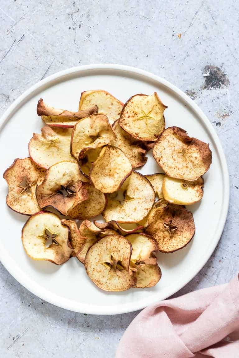 a plate of air fryer apple chips on white parchment