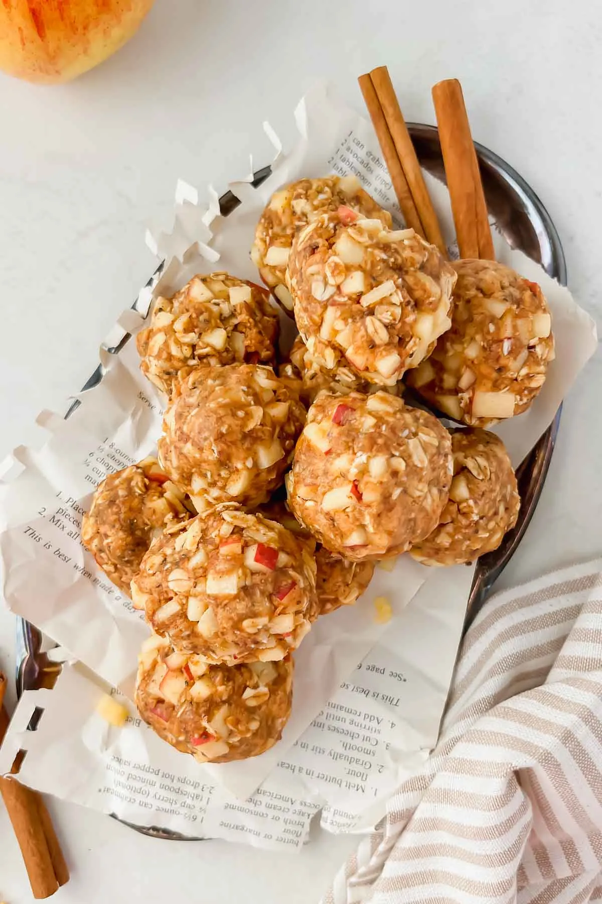 a silver tray of apple peanut butter energy bites, cinnamon sticks on the side.