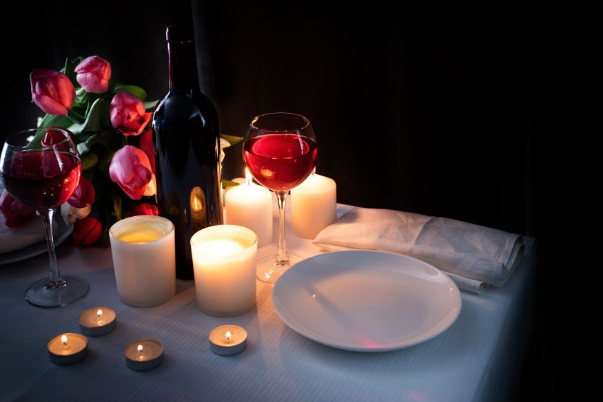 a candlelight dinner table for two set with candles, wine, and flowers