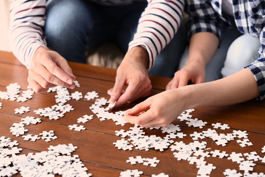 Young couple doing a puzzle together on a wooden coffee table