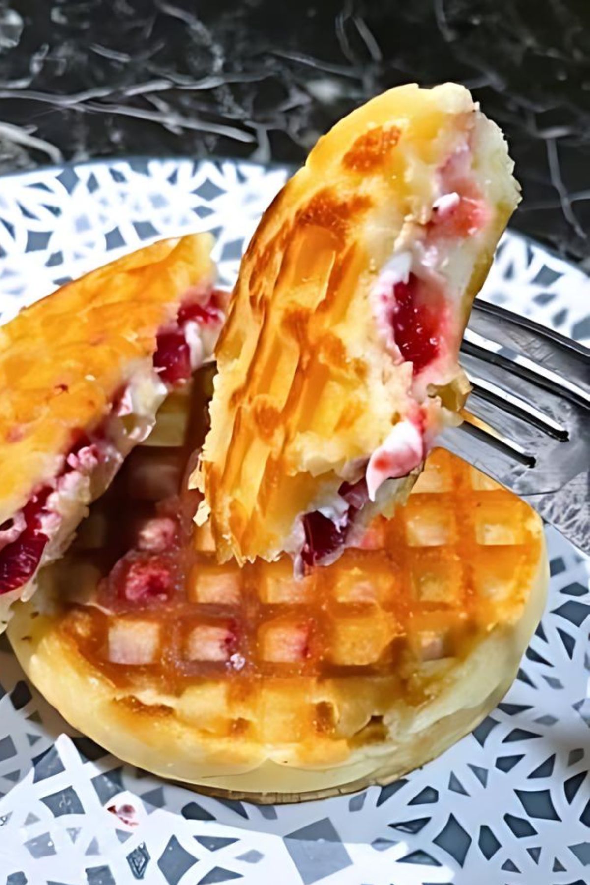 A sweet waffle grilled cheese sandwich cut in half to show the gooey filling