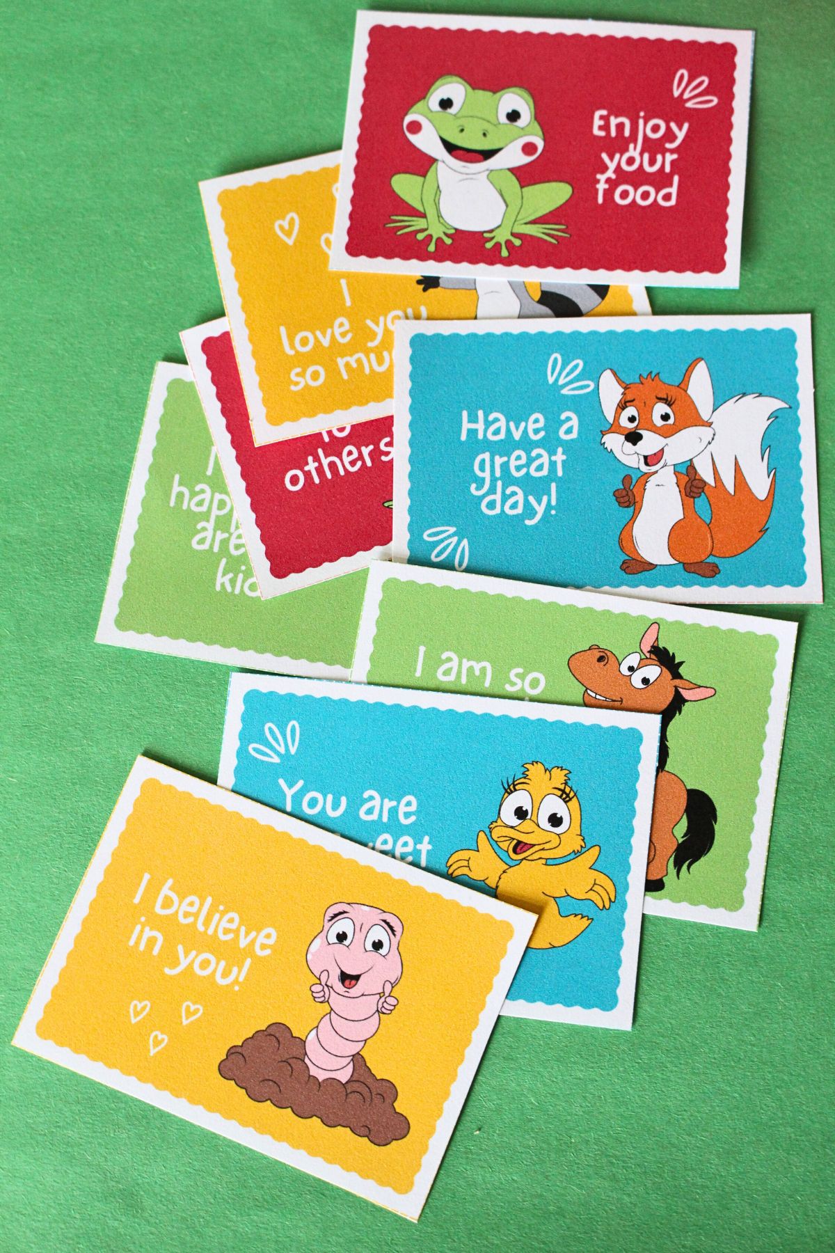 8 printable lunchbox notes for kids cut out and laying on a bright green sheet of paper