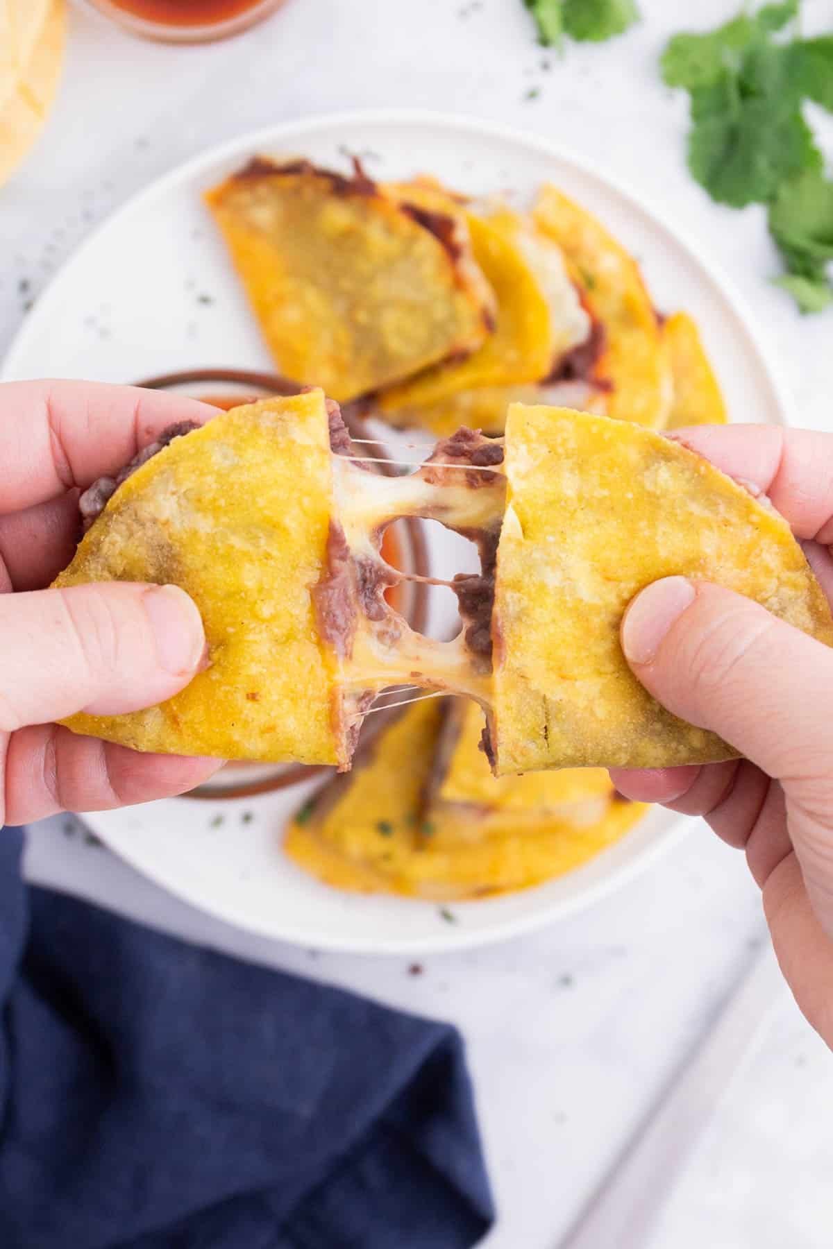 a corn tortilla quesadilla being pulled apart to show the melted cheese filling.