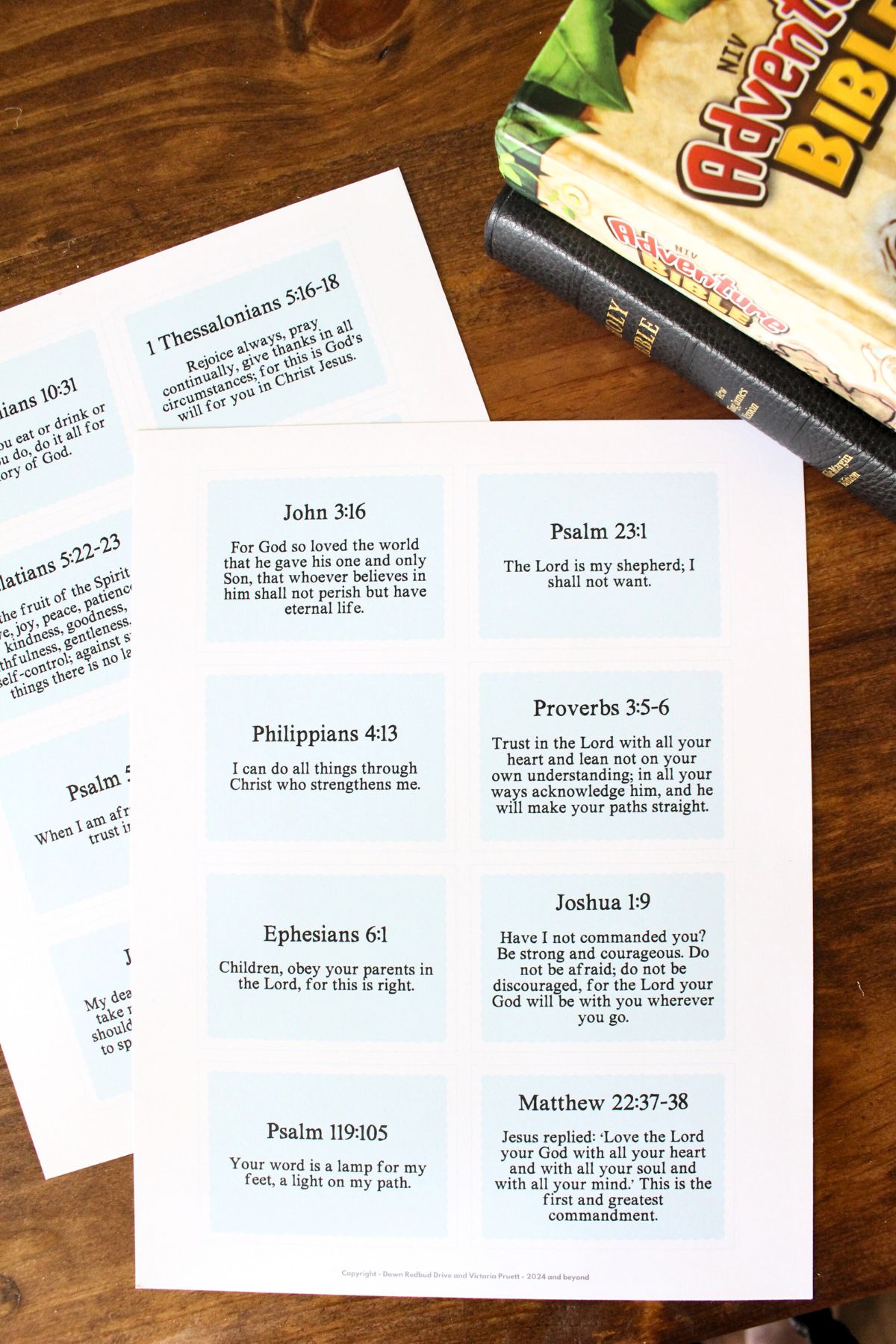 2 sheets of printable bible verse cards that have not been cut out yet, 2 bibles are in the background