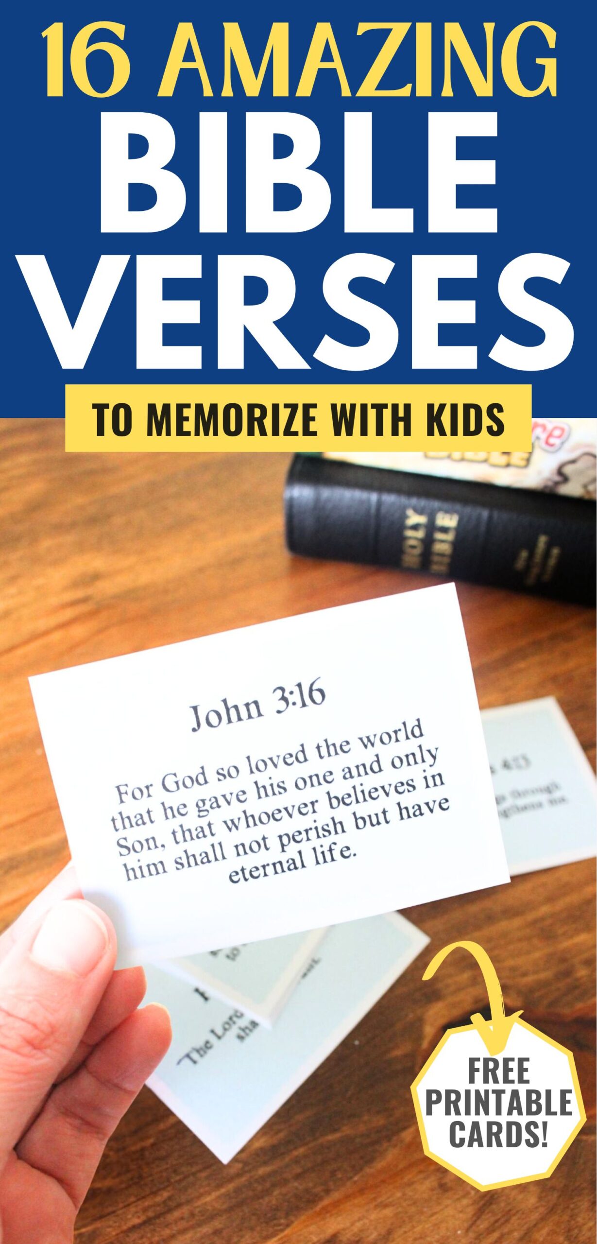 Small card cut out with a bible verse on it, john 3:16 for God so loved the world that he gave his one and only Son, that whoever believes in him shall not perish but have eternal life. The card is being held in a hand, you can see other cards in the background and 2 bibles stacks on top of each other. A text overlay on the image says 16 amazing bible verses to memorize with kids, free printable cards