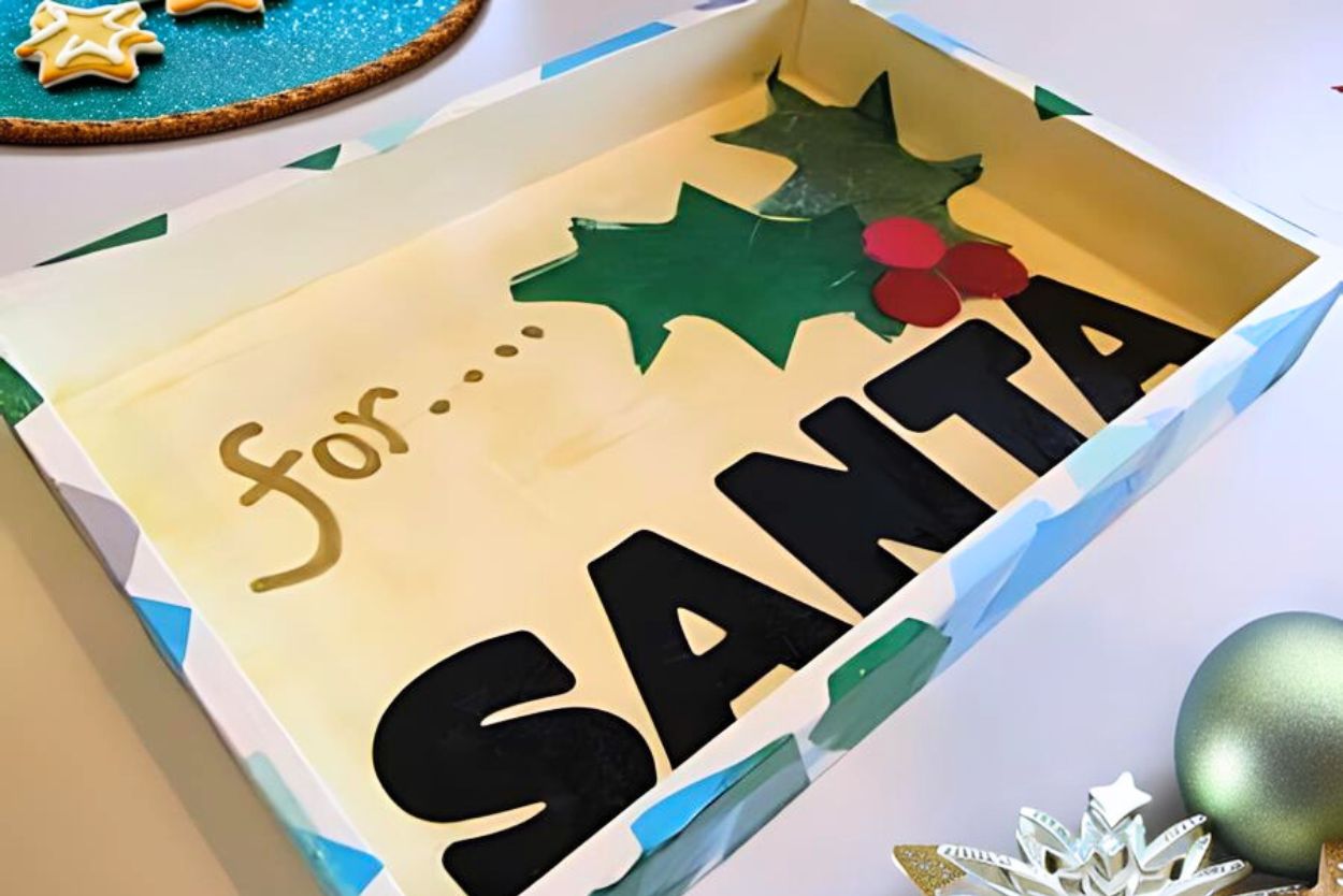 a wooden christmas cookie tray with the words for santa on the top and some paper holly glued to the top.