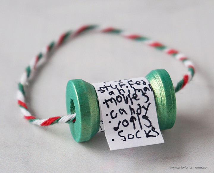 Thread spool painted to look like a scroll with a paper christmas list taped on and turned into a christmas ornament