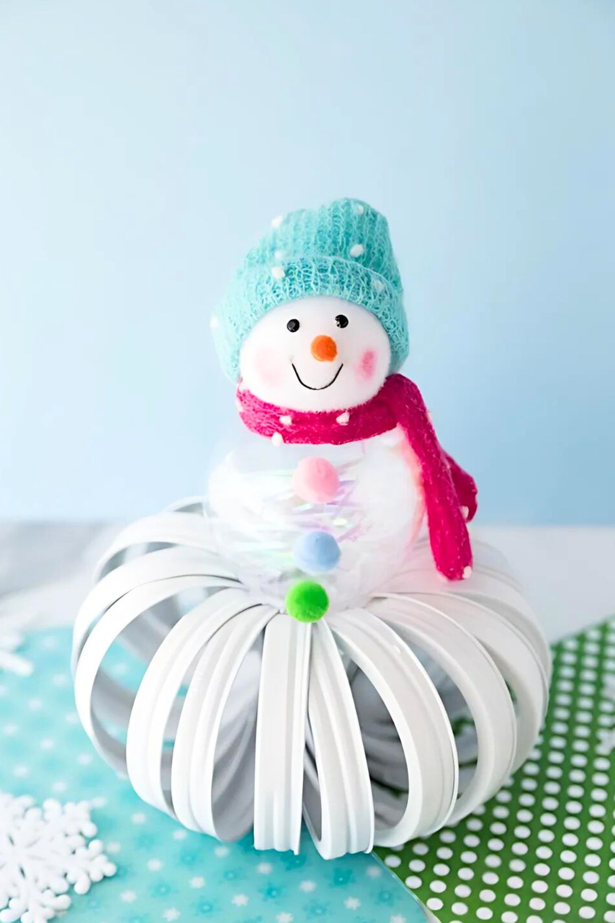 a winter snowman made out of mason jar lids and Christmas ornaments